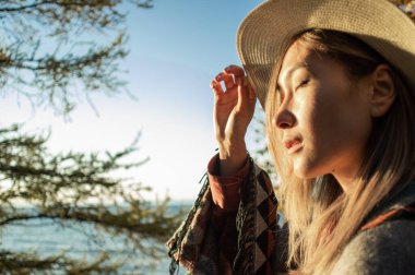 Gün batımında şapkalı Asyalı kadını yakından izle.