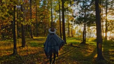 Sonbahar ormanında şapkalı ve pançolu bir kız.