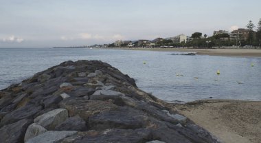 Deniz kenarındaki köy ve gökyüzü arkaplanlı taştan dalgakırana yakın çekim