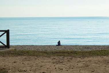 Yalnız kadın sahilde kumsalda oturuyor.