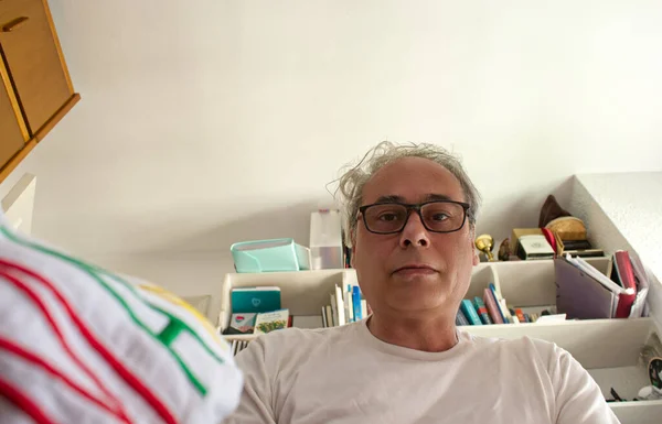 Olgun bir adam odaya girip elbiselerini çekmeceye yerleştiriyor.