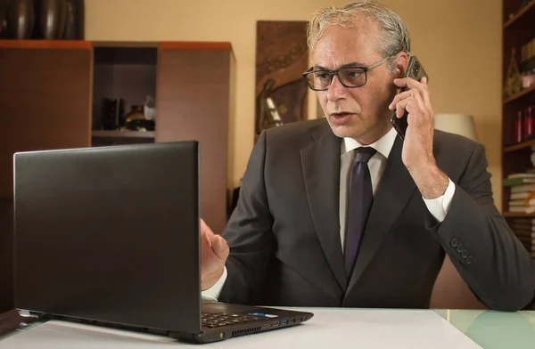 İş adamı evden bilgisayarlı ve cep telefonlu telgraf çekiyor.