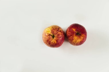 Yukarıdan bakıldığında beyaz arkaplanda damlaları olan iki kırmızı elma önplanı