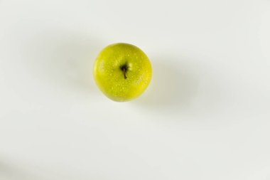 Yukarıdan bakıldığında beyaz arkaplanda damlaları olan yeşil elma önplanı