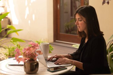 Güneşli bir günde dizüstü bilgisayar kullanan bir kadın.