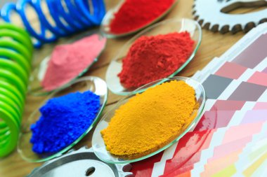 Toz boya kaplı metal parçaları ile cam tabakta ve renk tablosu yığını.