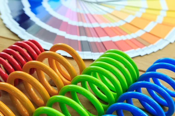 Metal, piezas de resorte del coche recubiertas con recubrimiento en polvo y carta de colores sobre fondo de madera — Foto de Stock