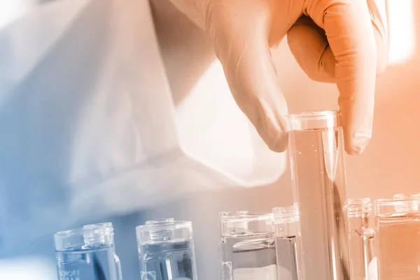 Guante de mano sosteniendo los tubos de ensayo en el laboratorio — Foto de Stock