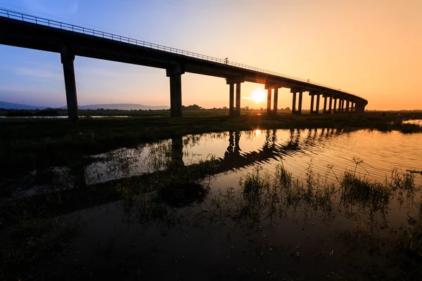 Τρένο γέφυρα πάνω από το φράγμα στο ηλιοβασίλεμα στην Ταϊλάνδη Royalty Free Εικόνες Αρχείου