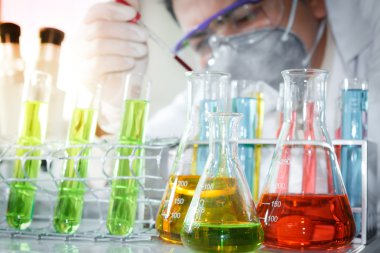 bir araştırmacı laboratuvar odasında örnek analiz ediyor.