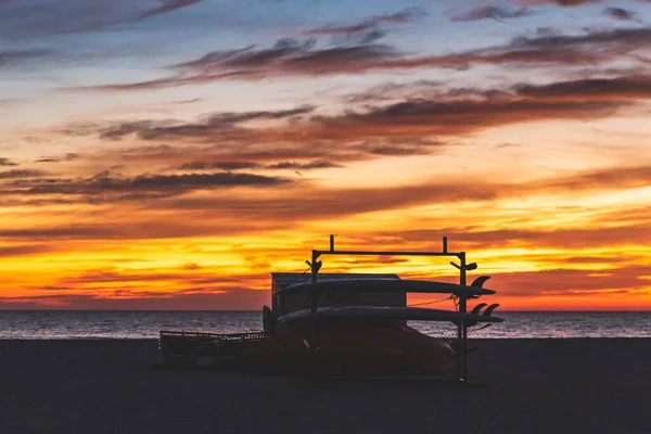 Σανίδες surf silhouetted κατά ζωντανή κίτρινο πορτοκαλί ουρανό με σύννεφα κατά το ηλιοβασίλεμα — Φωτογραφία Αρχείου