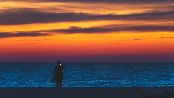 L'uomo scatta foto con telefono in vacanza in spiaggia, tramonto silhouette — Foto Stock