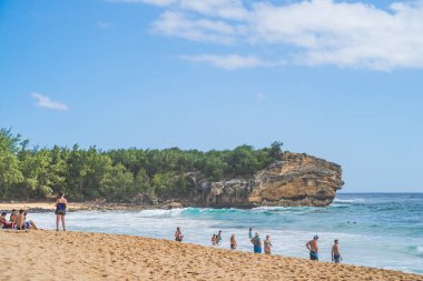 Turistler Poipu 'daki Pasifik Okyanusu' nun tadını çıkarırken Batık Sahili manzarası.
