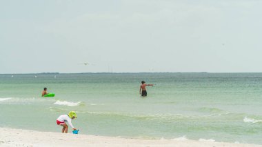 Sarkık şapkalı küçük çocuk kumsalda kumsalda oynuyor.