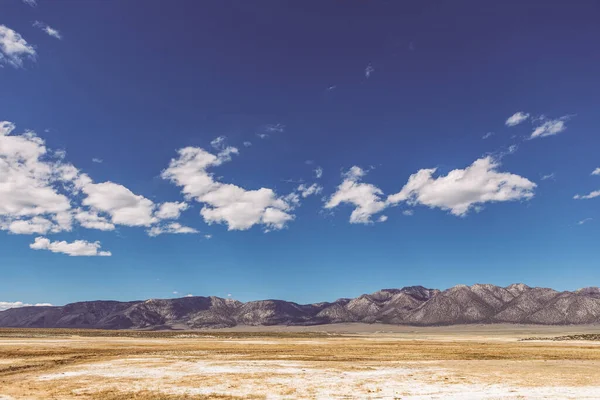 Arid plains against Sierra Nevada Mountains and blue sky with clouds — 스톡 사진