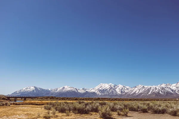 Arid plains against Sierra Nevada Mountains and clear blue sky — 스톡 사진