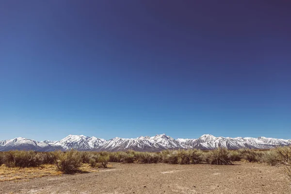 Arid plains against Sierra Nevada Mountains and clear blue sky — 스톡 사진