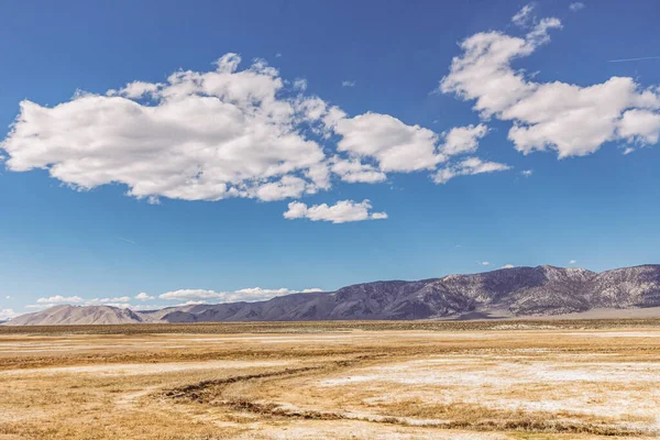 Arid plains against Sierra Nevada Mountains and blue sky with clouds — 스톡 사진