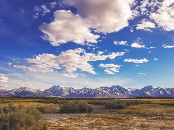 River runs though Arid plain against Sierra Nevada Mountains sky — 스톡 사진