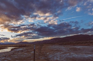 Nehir, Arid ovasında dramatik günbatımı gökyüzüne ve dağlara karşı akar.