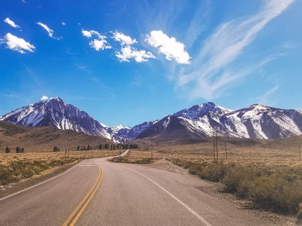 Road to Snow capped Sierra Nevada Mountains blue sky with clouds — 스톡 사진