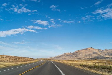 Kurak Sierra Nevadas 'da iki şerit yol Mavi gökyüzüne karşı dağlara çıkıyor