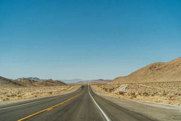 맑은 푸른 하늘 과산을 가로지르는 지평선까지 이어지는 사막 도로 — 스톡 사진