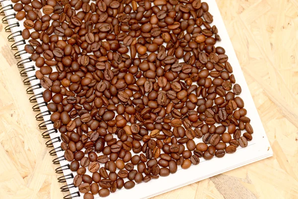 Grains de café sur un carnet, café noir frit — Photo