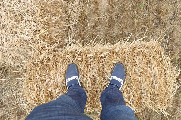 Men left foot pressed on straw bales.