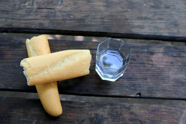 Glas vatten, bröd, dela i två, med bröd-ringar på fliken — Stockfoto