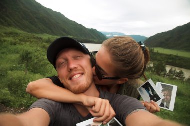 Young couple hiking taking selfie on polaroid,retro pic,Instagram filters,girl kissing her man,lovely couple,holding each other 