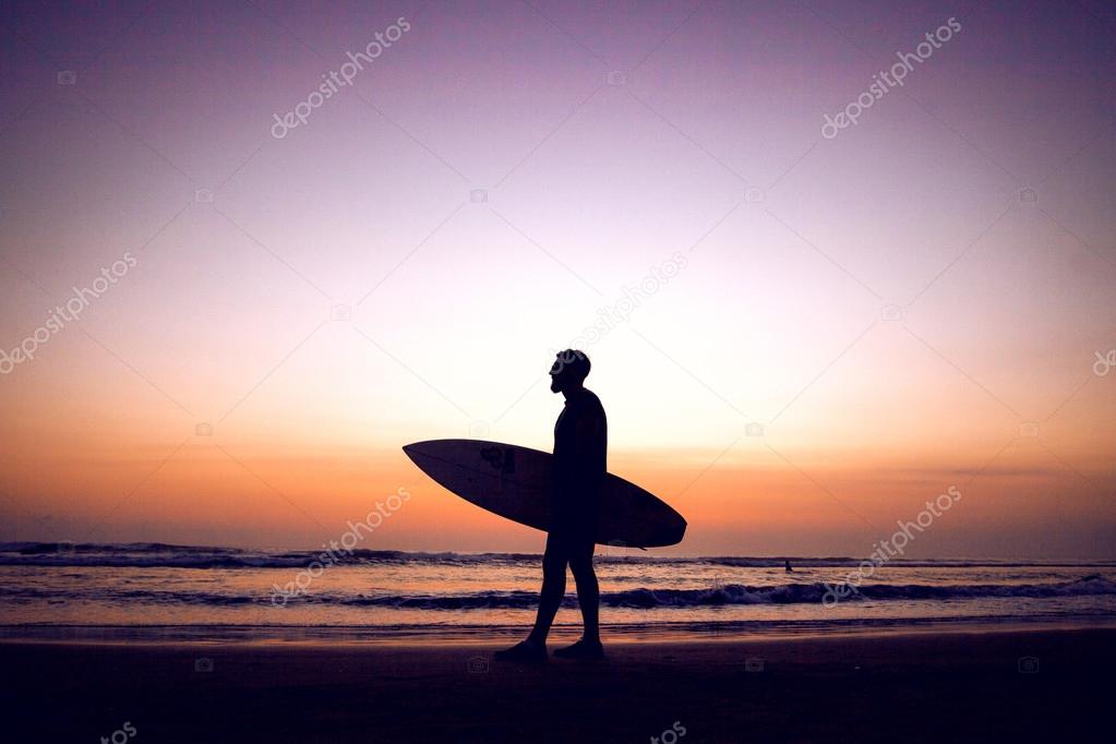 Silhouette of surfer man at sunset