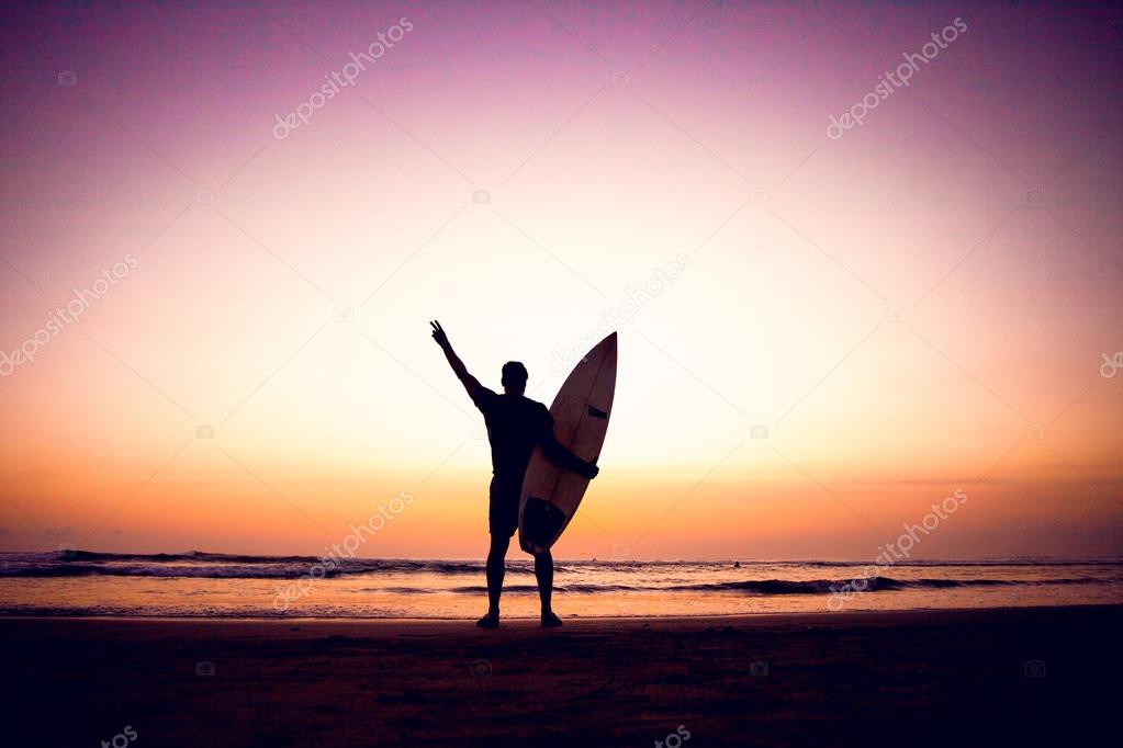 Silhouette of surfer man at sunset