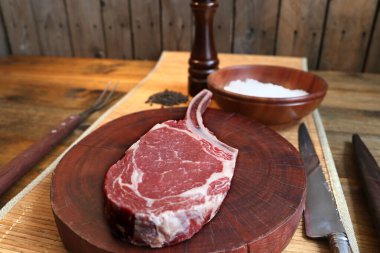 Pirzola. Çiğ kaburga gözü bifteği ve barbekü için kemik. Ahşap arka planda.