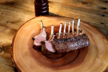 Fransız Rack. Kuzu kaburgaları ahşap arka planda ızgara. Küçük bıçak, tuz ve biberle birlikte..