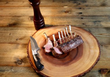 Fransız Rack. Kuzu kaburgaları ahşap arka planda ızgara. Küçük bıçak, tuz ve biberle birlikte..