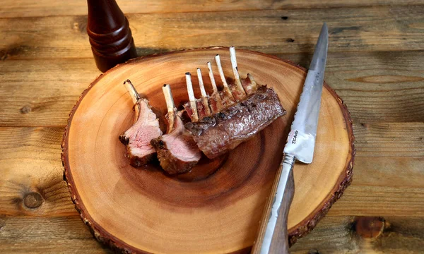 Fransız Rack. Kuzu kaburgaları ahşap arka planda ızgara. Küçük bıçak, tuz ve biberle birlikte..