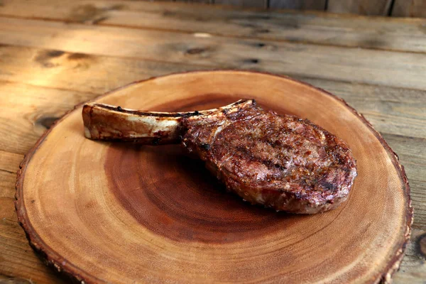 Prime Rib. Rare Rib Eye steak with bone grilled in barbecue. On wooden background.