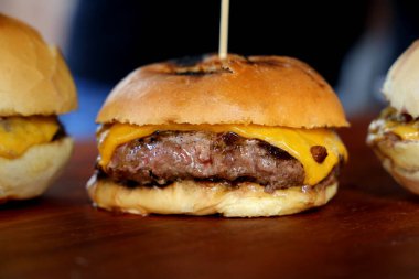 Peynirli burger ve ızgarada pişirilmiş ekmek. Yan görüş. Kapatın. Ahşap arka planda.