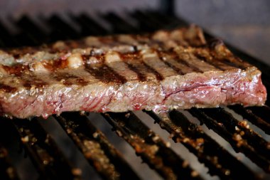 Güzel sulu Picanha, ızgaranın üstünde ızgara izleri ve arka planda parlayan kömürle yakın çekim yap.