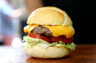 Tahta arka planda peynirli salata burgeri.