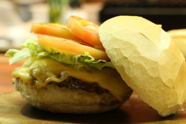 Peynirli hamburger, domates ve ızgarada yapılan ekmek. Yan görüş. Kapat..