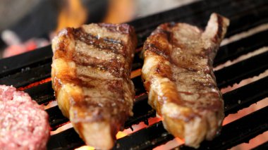 Picanha ızgaranın üstünde ızgara izleriyle yaklaş. Arka planda parlayan kömür var.