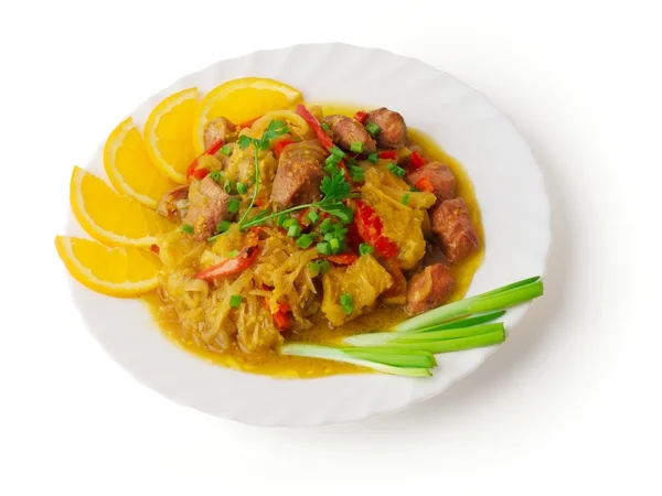 Gulash de carne con col, pimienta búlgara naranja y roja decorado con cebolla, naranja, perejil colocado en el plato sobre fondo blanco —  Fotos de Stock