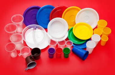 Kırmızı bir arka plan üzerinde renkli plastik mutfak eşyaları