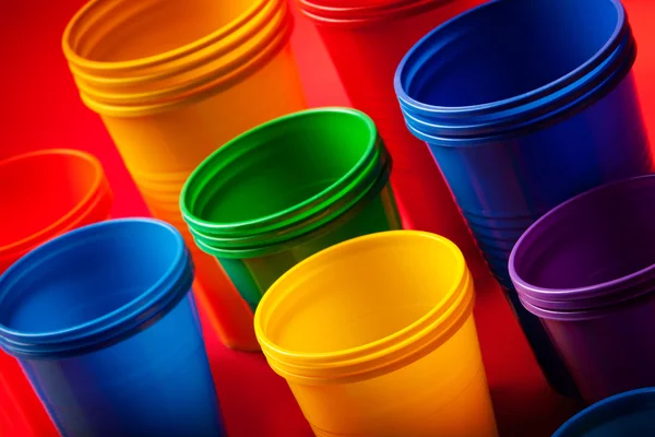 Colored plastic glasses on red background — Stock Photo, Image