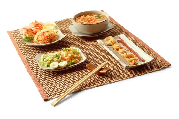 Asiatiska affärslunch med lax teriyaki, ris med grönsaker, skull dzosuy, yakitori ika och pinnar på mattor över vit bakgrund — Stockfoto