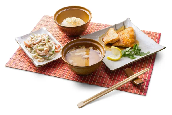 Aziatische zakenlunch met rijst, miso soep, vlees tempura, gedze en stokjes op de matten op witte achtergrond — Stockfoto