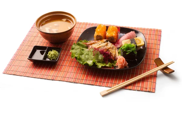 Asiatiska affärslunch med misosoppa, sushi, maguro, sallad och pinnar på mattor över vit bakgrund — Stockfoto