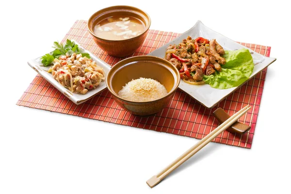 Aziatische zakenlunch met rijst, miso soep, gekookte vlees, garnaal tempura en stokjes op de matten op witte achtergrond — Stockfoto